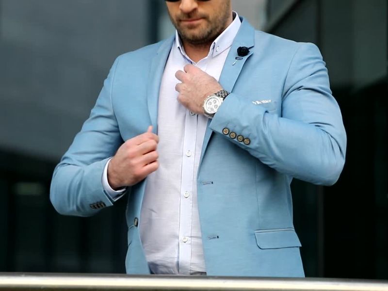 Ova slika prikazuje muškarca u svetloplavom sako-u, beloj košulji i modernom satu. Izgleda elegantno i moderno, idealno za ležerne poslovne ili poluformalne prilike.